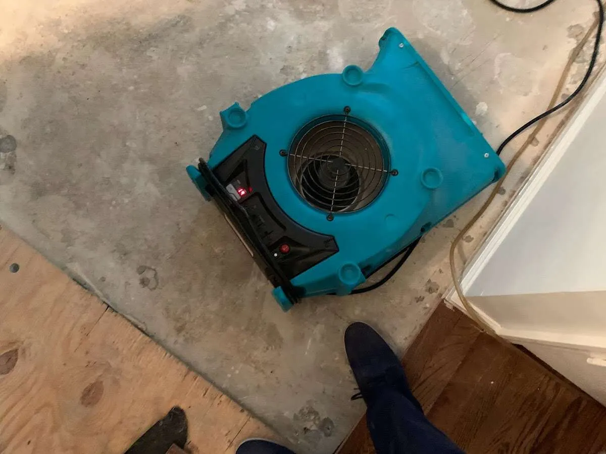 Air mover drying subfloor during Commercial Water Damage Restoration in Grass Lake